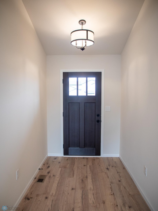 doorway to outside featuring light wood-style floors, visible vents, and baseboards