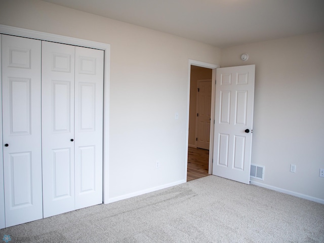 unfurnished bedroom featuring carpet, visible vents, baseboards, and a closet