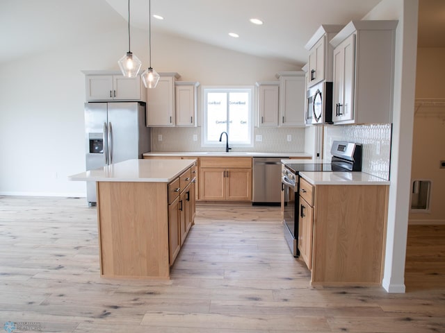 kitchen featuring a sink, light wood-type flooring, vaulted ceiling, light countertops, and appliances with stainless steel finishes