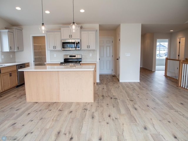 kitchen featuring light wood finished floors, light countertops, appliances with stainless steel finishes, and tasteful backsplash