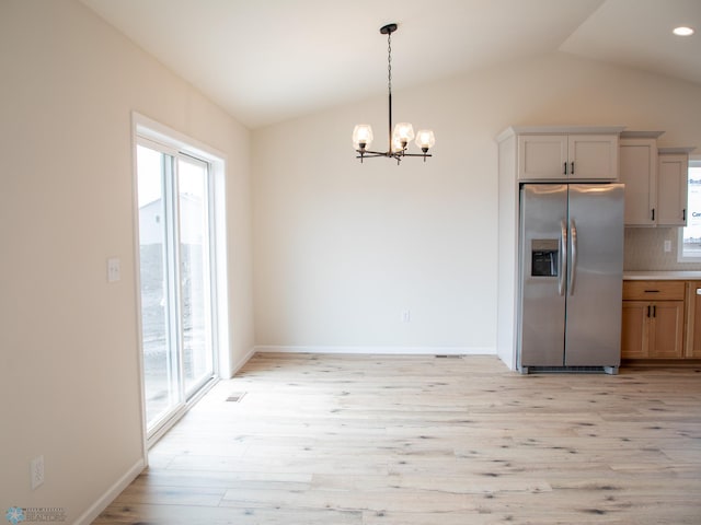 kitchen featuring stainless steel fridge with ice dispenser, lofted ceiling, and a healthy amount of sunlight