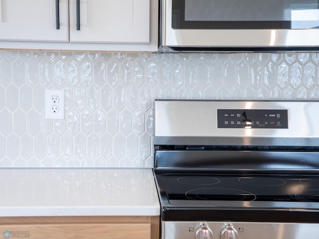 interior details with tasteful backsplash, white cabinets, and appliances with stainless steel finishes