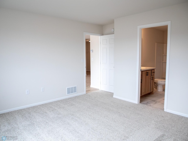 unfurnished bedroom with baseboards, connected bathroom, visible vents, and light colored carpet