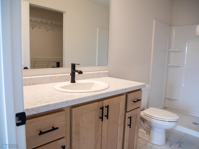 bathroom with a shower stall, toilet, vanity, and marble finish floor