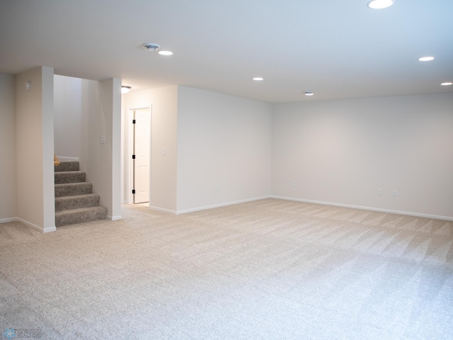 finished below grade area featuring baseboards, stairway, recessed lighting, and light colored carpet