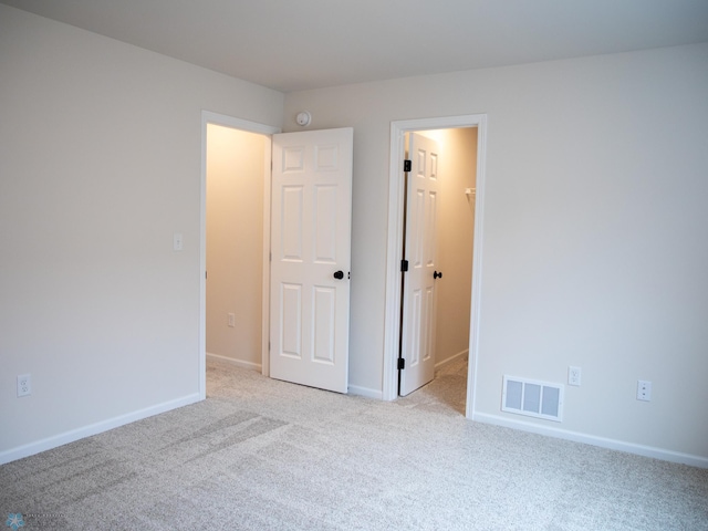 unfurnished room with baseboards, light carpet, and visible vents