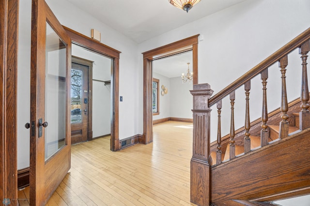 entryway with plenty of natural light, a chandelier, light wood finished floors, and stairs