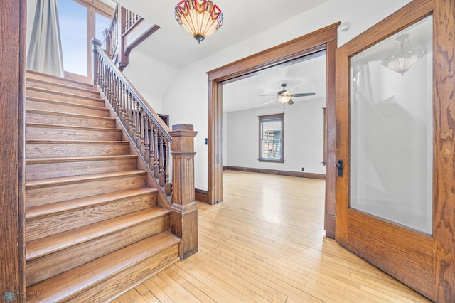 staircase featuring hardwood / wood-style flooring, ceiling fan, and baseboards