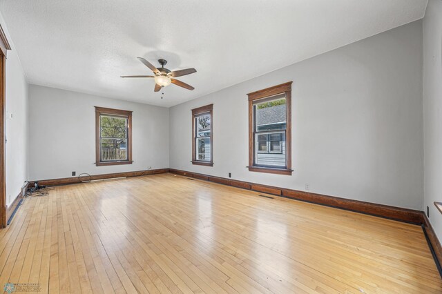 empty room with a ceiling fan, light wood-style floors, and baseboards