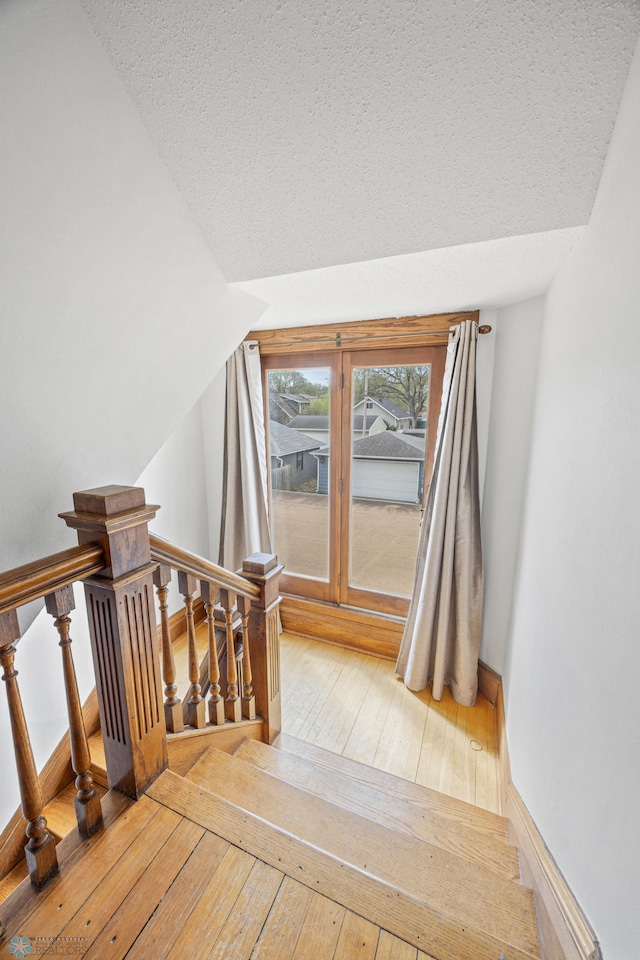 additional living space featuring hardwood / wood-style floors, a textured ceiling, and stairway