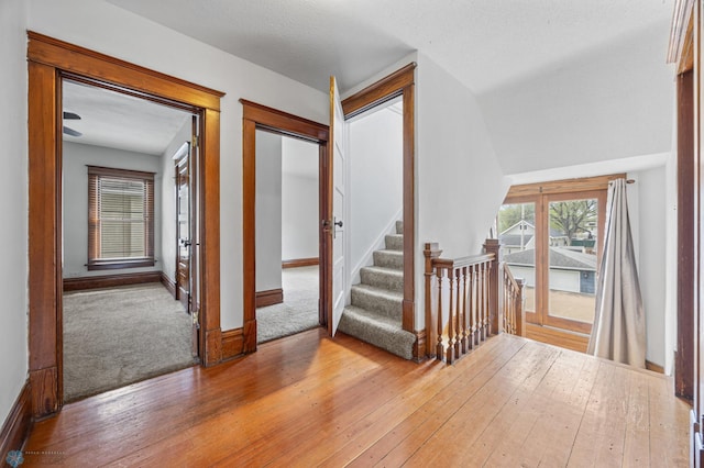 corridor with hardwood / wood-style floors, baseboards, carpet flooring, and stairs