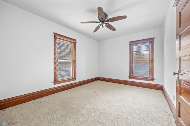 carpeted spare room featuring baseboards and a ceiling fan