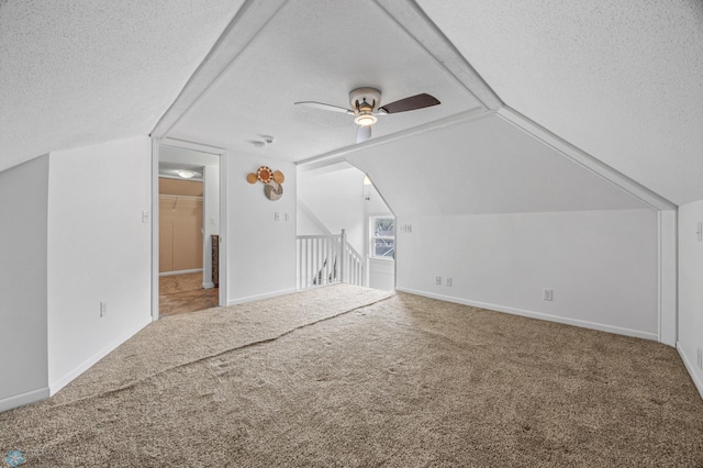 additional living space with a textured ceiling, a ceiling fan, carpet, vaulted ceiling, and baseboards