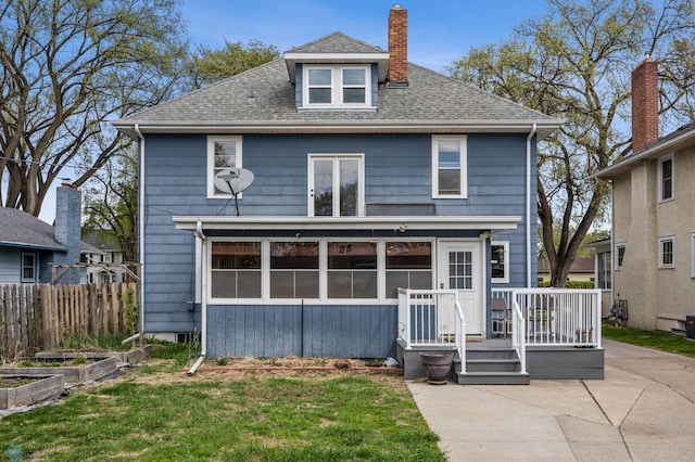 back of property featuring roof with shingles, a chimney, and a garden