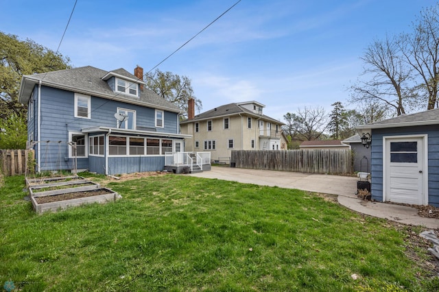 back of house featuring a garden, a sunroom, a chimney, a deck, and a patio