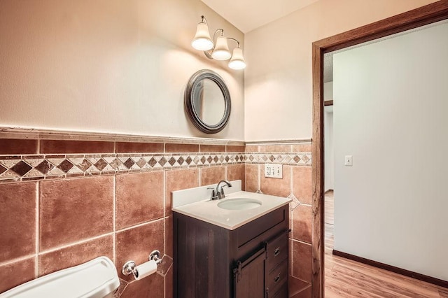 2108 Gunflint Trl, Brooklyn Park, MN 55444 - half bathroom featuring tile walls, vanity, wood finished floors, and wainscoting