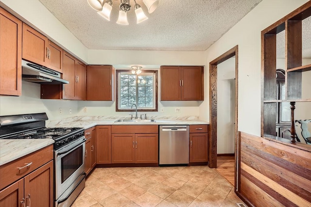 2108 Gunflint Trl, Brooklyn Park, MN 55444 - kitchen with stainless steel appliances, under cabinet range hood, brown cabinets, a textured ceiling, and light tile patterned flooring