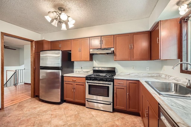 2108 Gunflint Trl, Brooklyn Park, MN 55444 - kitchen with stainless steel appliances, under cabinet range hood, light countertops, brown cabinets, and a textured ceiling