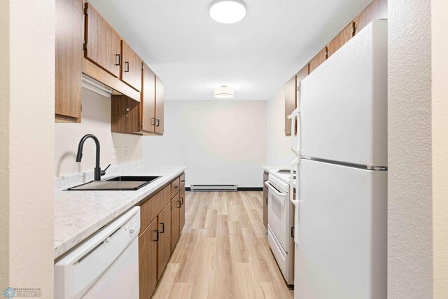 kitchen featuring white appliances, a sink, baseboard heating, light countertops, and light wood finished floors