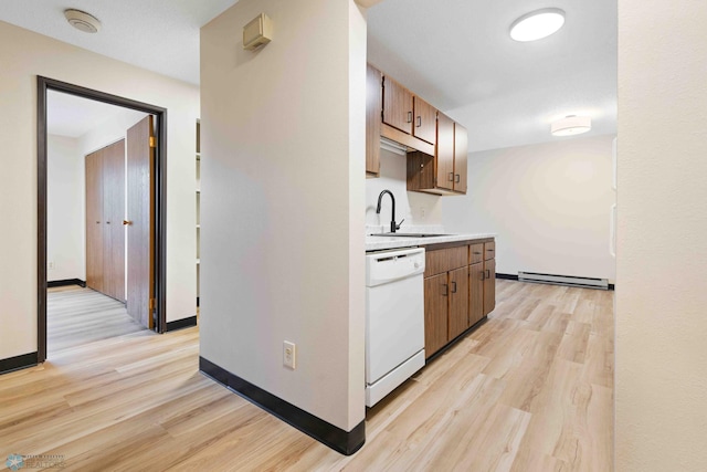 kitchen featuring white dishwasher, baseboard heating, light countertops, a sink, and light wood-style flooring