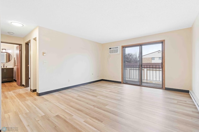 empty room with an AC wall unit, light wood-style flooring, and baseboards