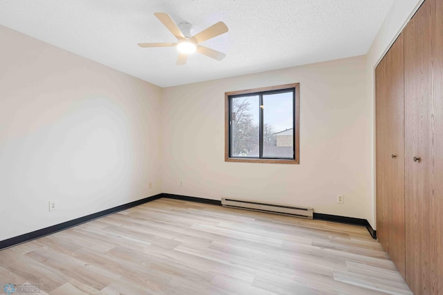 unfurnished bedroom featuring a baseboard heating unit, a closet, light wood-style flooring, ceiling fan, and baseboards