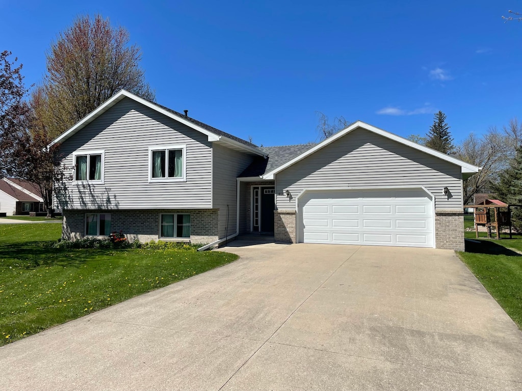 405 1st Ave SE, Grand Meadow, MN 55936 - tri-level home with a front lawn, concrete driveway, brick siding, and a garage