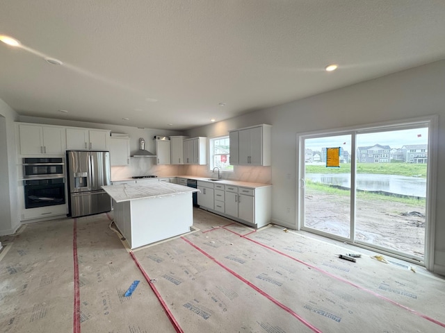 3112 Sugar Maple Dr, Chaska, MN 55318 - kitchen featuring appliances with stainless steel finishes, wall chimney exhaust hood, white cabinets, a center island, and a water view