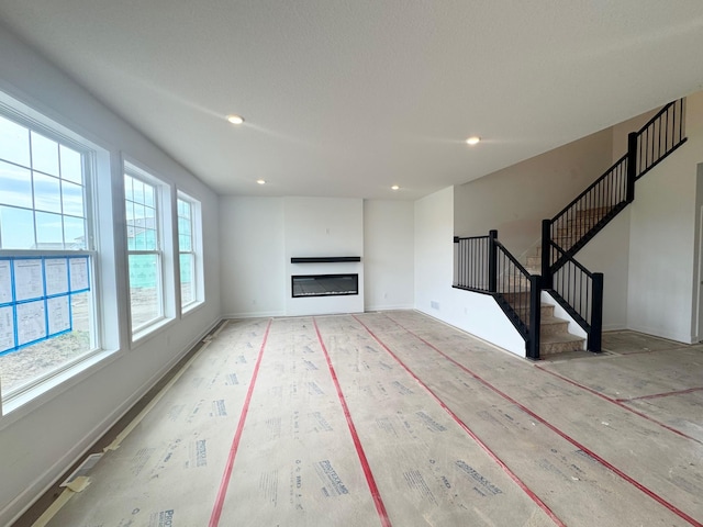 3112 Sugar Maple Dr, Chaska, MN 55318 - unfurnished living room featuring stairs, recessed lighting, and a glass covered fireplace