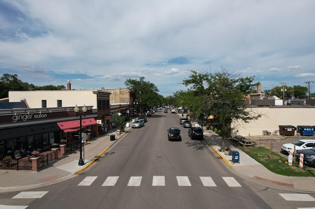 view of asphalt road with sidewalks, curbs, and street lighting