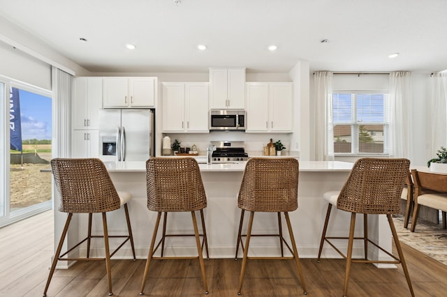 2146 Tyrone Dr, Shakopee, MN 55379 - kitchen with appliances with stainless steel finishes, light wood-type flooring, an island with sink, light countertops, and white cabinetry