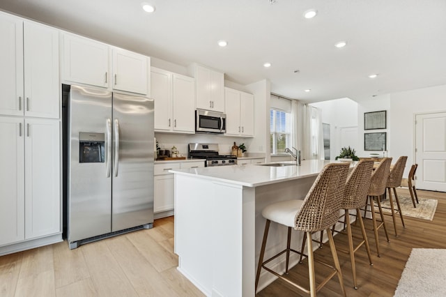 2146 Tyrone Dr, Shakopee, MN 55379 - kitchen with appliances with stainless steel finishes, an island with sink, light wood-type flooring, white cabinetry, and recessed lighting