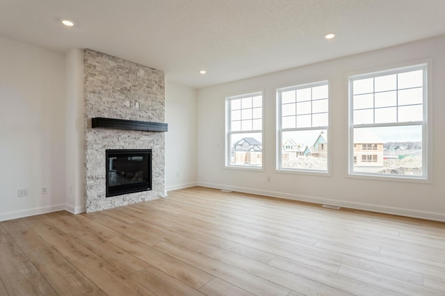 20092 67th Ave, Corcoran, MN 55340 - unfurnished living room with light wood finished floors, plenty of natural light, a fireplace, baseboards, and recessed lighting
