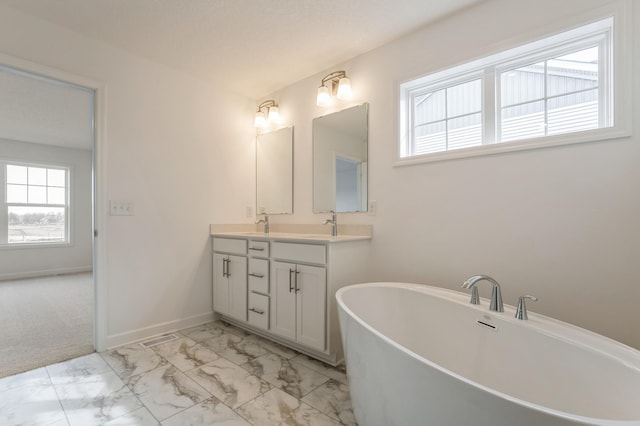 20092 67th Ave, Corcoran, MN 55340 - full bathroom with marble look tile flooring, double vanity, a freestanding tub, and baseboards