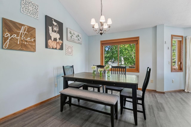 dining space featuring light wood-type flooring, a chandelier, lofted ceiling, and baseboards
