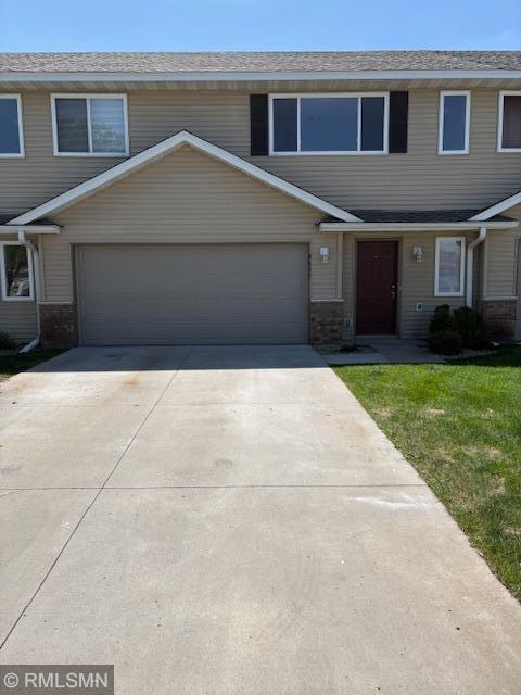 view of property featuring a garage, concrete driveway, and a front lawn