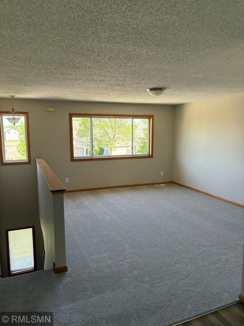 carpeted empty room with a textured ceiling and baseboards