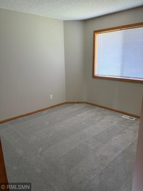 unfurnished room with a textured ceiling, carpet flooring, and baseboards