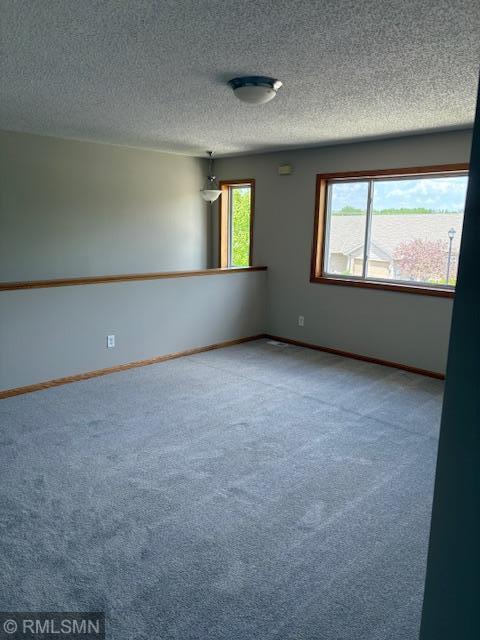 carpeted spare room with baseboards and a textured ceiling