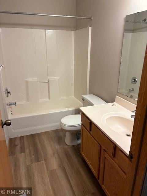 bathroom featuring toilet, wood finished floors, vanity, and shower / bathtub combination