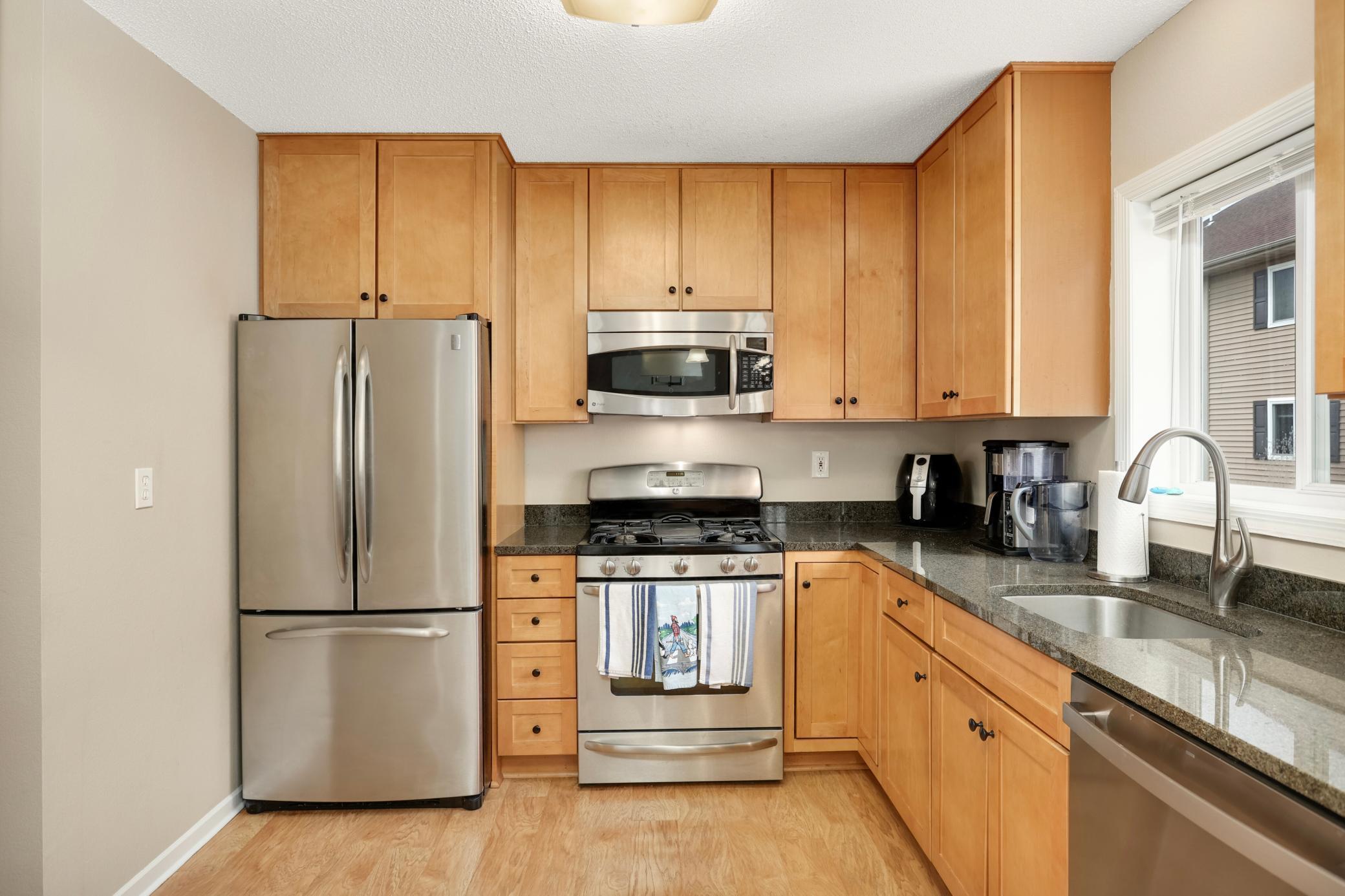 6477 Regency Ln, Eden Prairie, MN 55344 - kitchen with stainless steel appliances, a sink, light wood-type flooring, and dark stone counters