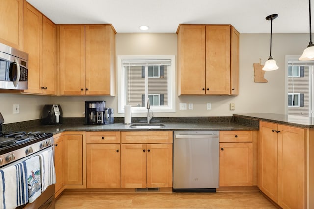 6477 Regency Ln, Eden Prairie, MN 55344 - kitchen featuring stainless steel appliances, a sink, light wood finished floors, a peninsula, and dark stone countertops