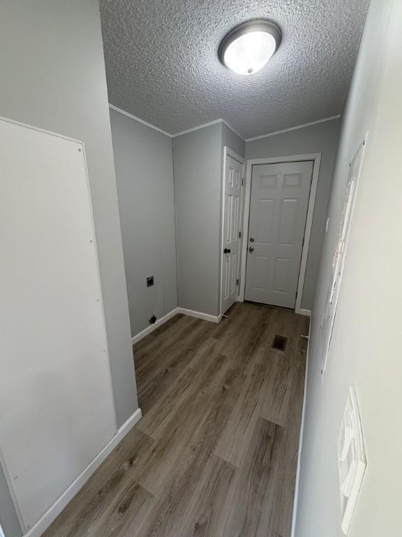 clothes washing area featuring a textured ceiling, wood finished floors, and baseboards