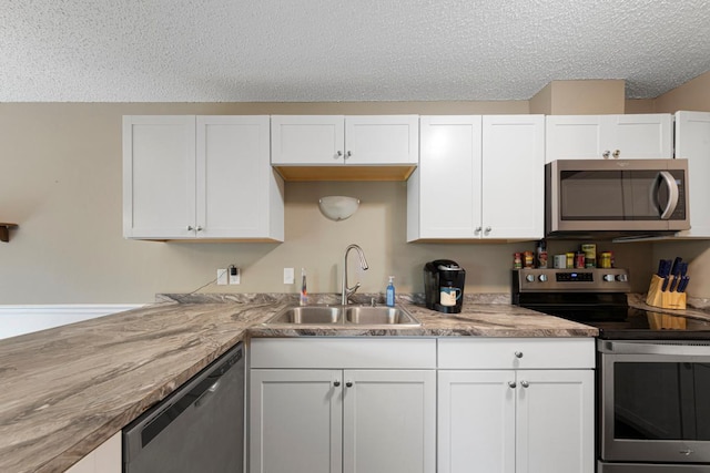 1508 Pheasantwood Trl, Northfield, MN 55057 - kitchen with stainless steel appliances, a sink, white cabinetry, a textured ceiling, and light countertops