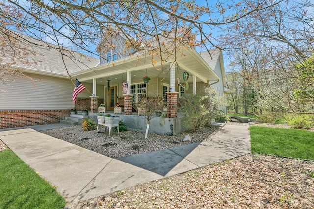 view of home's exterior with a porch, brick siding, and a shingled roof