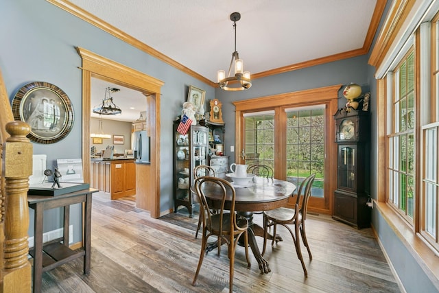 dining area with a chandelier, wood finished floors, ornamental molding, and baseboards