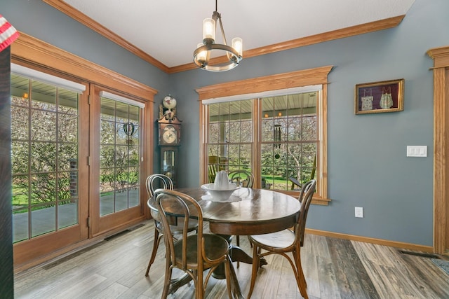 dining area featuring a chandelier, baseboards, crown molding, and wood finished floors