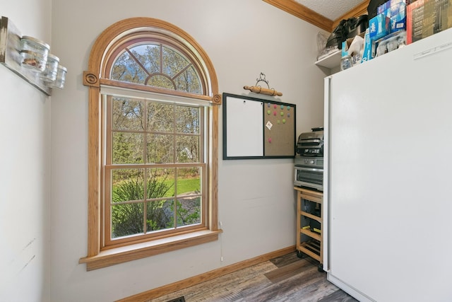 kitchen featuring wood finished floors, crown molding, and baseboards