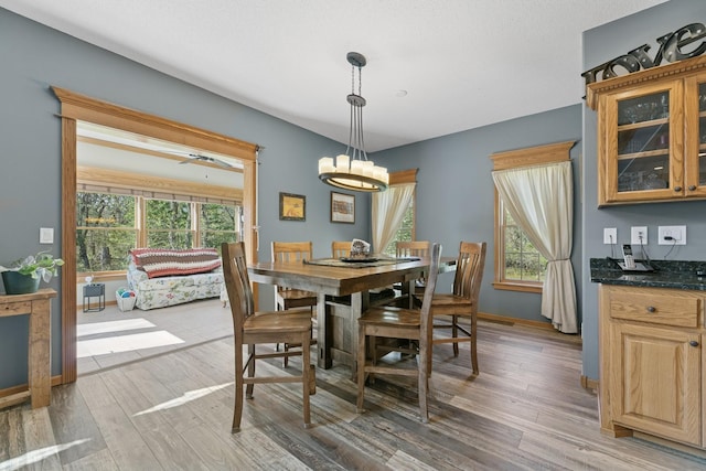 dining space with light wood-style flooring, a chandelier, and baseboards