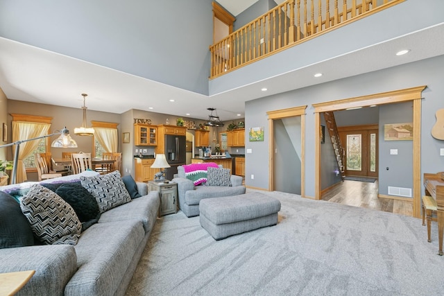 living area with plenty of natural light, light wood-style flooring, a high ceiling, and recessed lighting